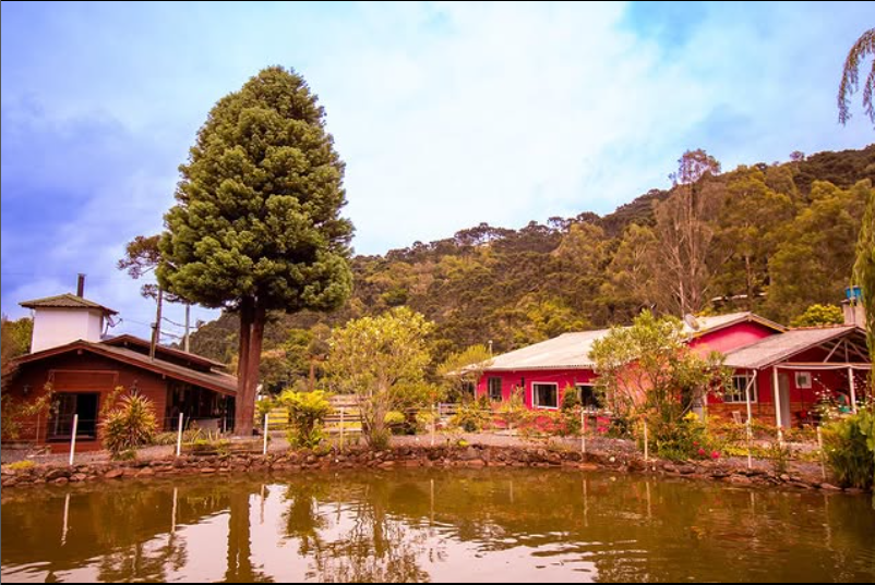 Vista da pousada Recanto do Riacho em Urubici, com lago, casas e montanha ao fundo